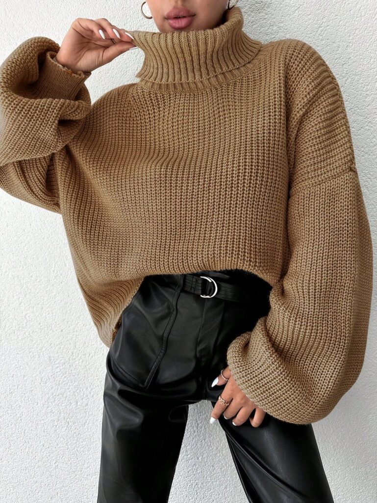 Un pull col roulé oversize beige-marron associé à un pantalon en similicuir noir et une ceinture élégante : un look automnal chic et moderne.